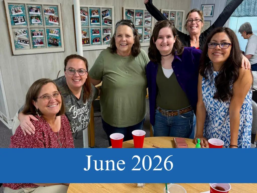 Women with their arms around each other sitting at a round table